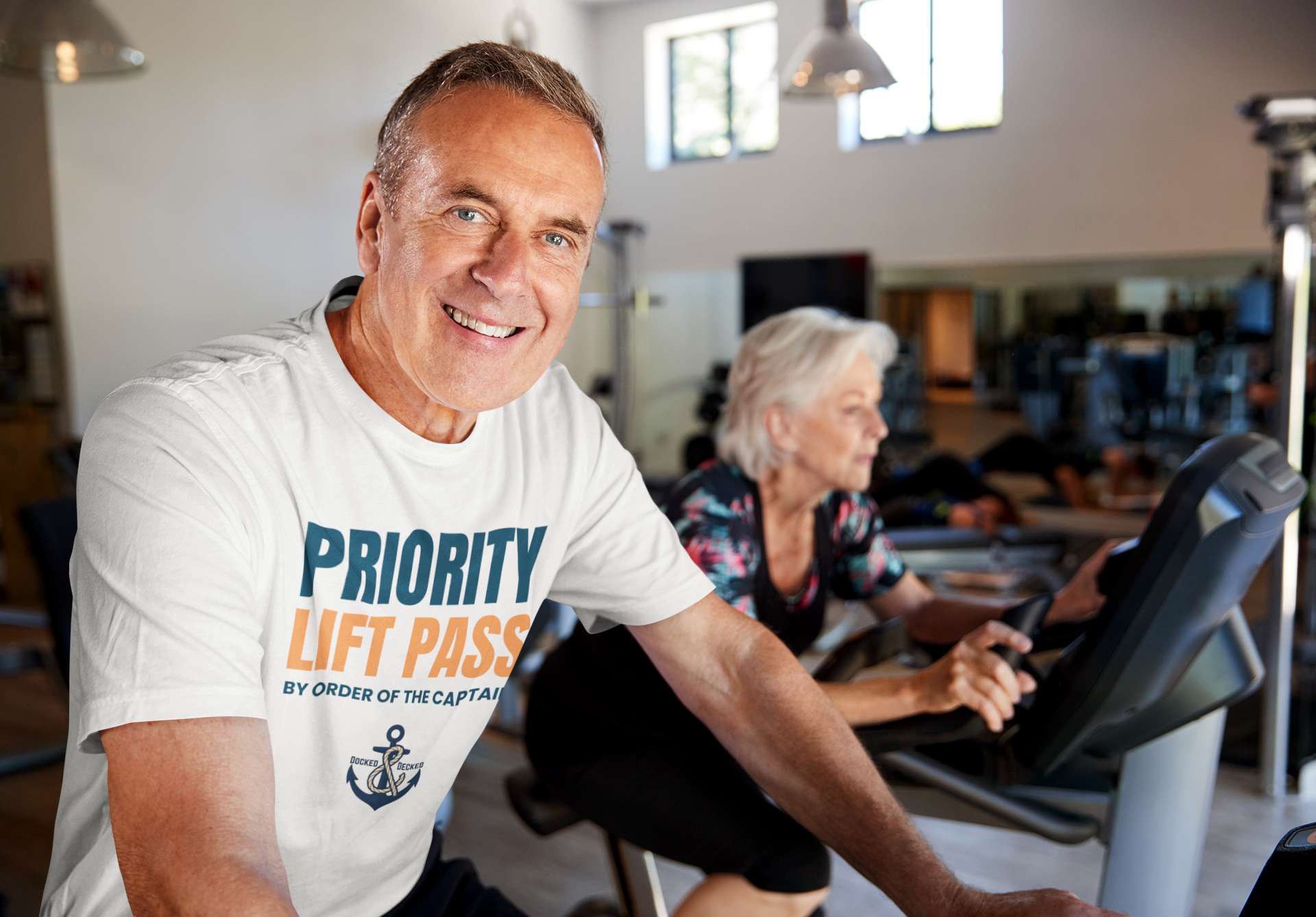 PRIORITY LIFT PASS White Cruise T Shirt Older man wearing a white Priority Lift Pass cruise T-shirt in a gym setting